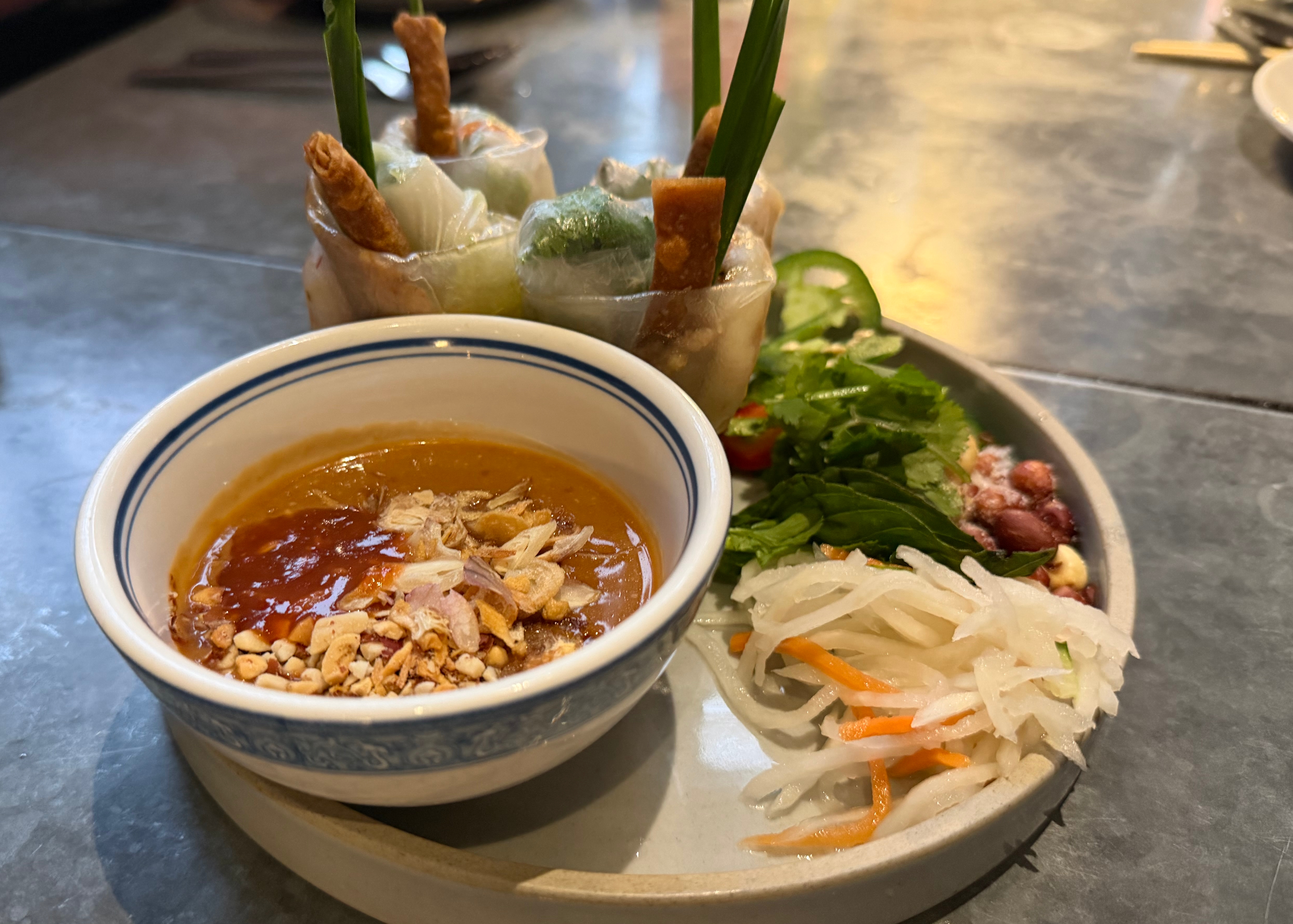 Vietnamese style spring rolls next to peanut sauce and pickled vegetables